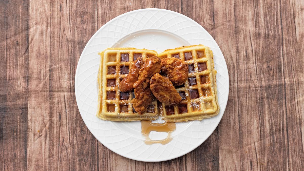 Crispy chicken tenders glazed and stacked on two fluffy waffles, dusted with powdered sugar.