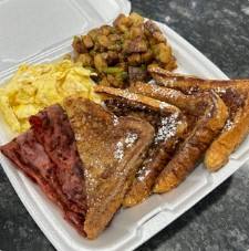 French toast platter with powdered sugar, crispy bacon, and eggs.